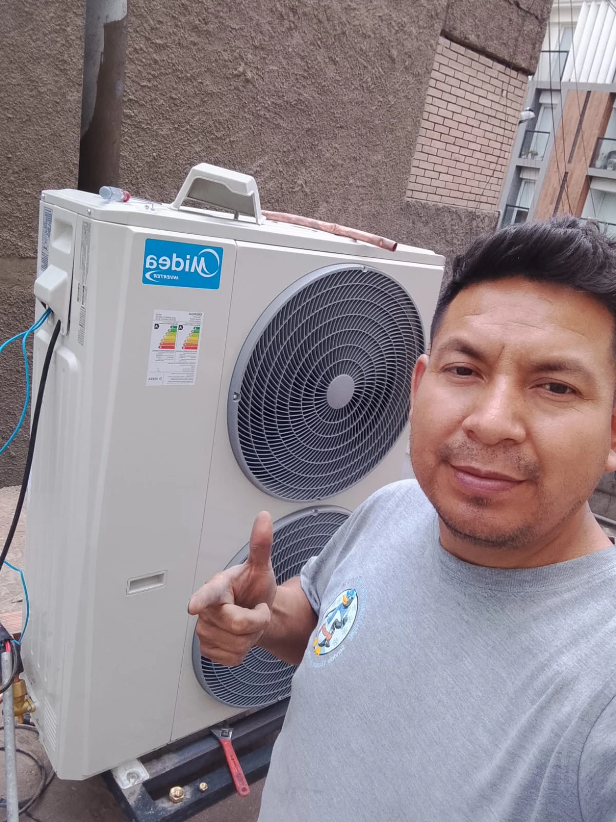 T&eacute;cnico junto a una unidad exterior de aire acondicionado